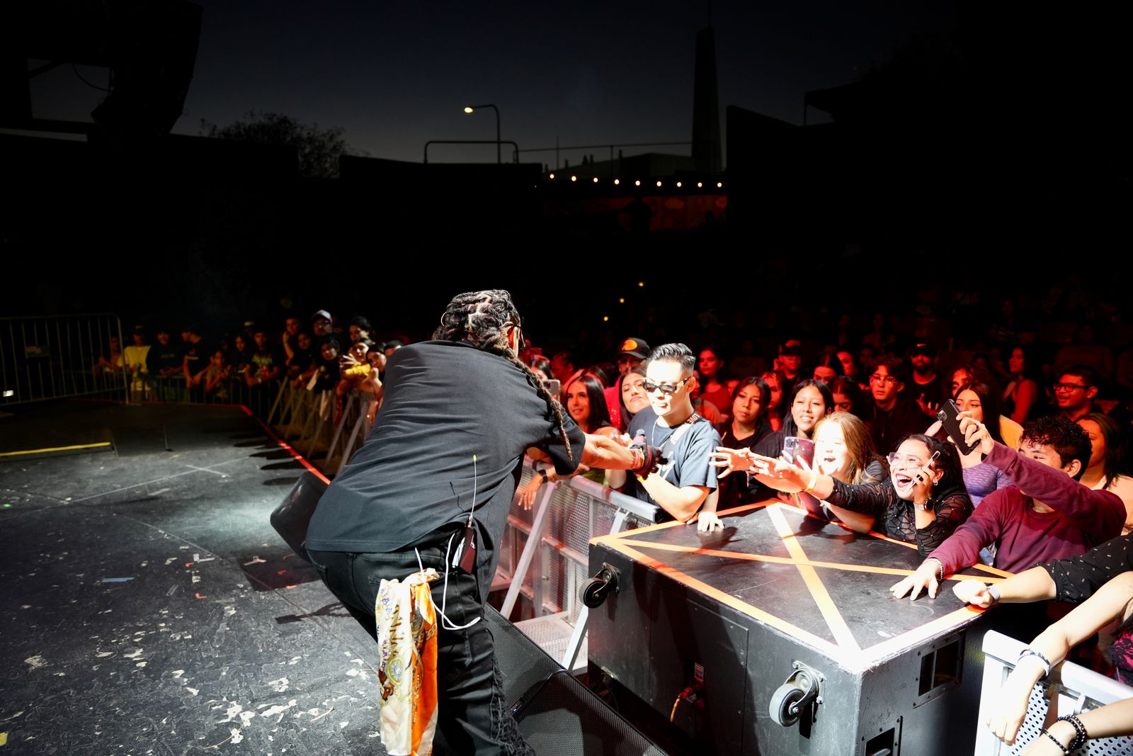 KILOHANA slapping hands with fans at the barricade at an outdoor show