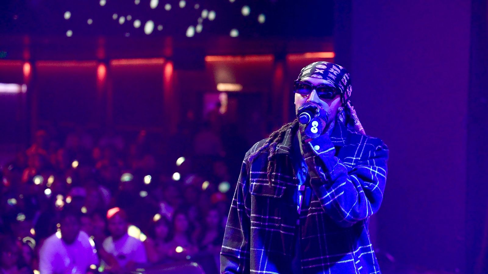 KILOHANA in sunglasses rapping on stage at The Novo under blue and purple light